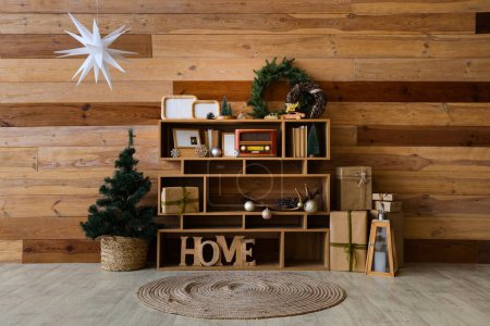 Photo for Shelving unit with vintage radio, books and Christmas decorations near wooden wall - Royalty Free Image