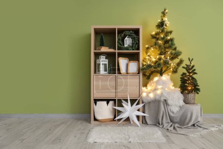 Photo for Wooden shelving unit, Christmas trees and decorations near green wall - Royalty Free Image