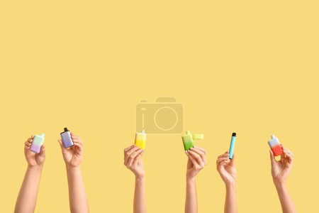 Téléchargez les photos : Mains féminines avec différentes cigarettes électroniques sur fond de couleur - en image libre de droit