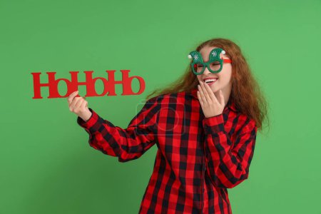Téléchargez les photos : Jeune femme en pyjama avec salutation de Noël sur fond vert - en image libre de droit