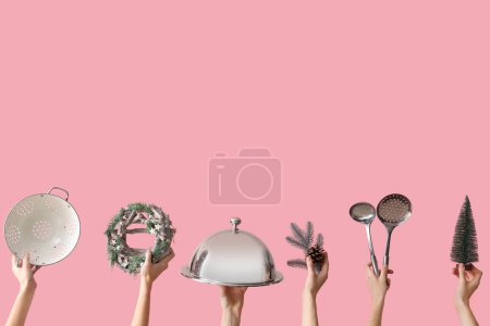Téléchargez les photos : Mains tenant des ustensiles de cuisine et des décorations de Noël sur fond rose - en image libre de droit