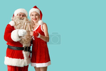 Téléchargez les photos : Père Noël et MRS Claus avec des verres de champagne sur fond bleu - en image libre de droit