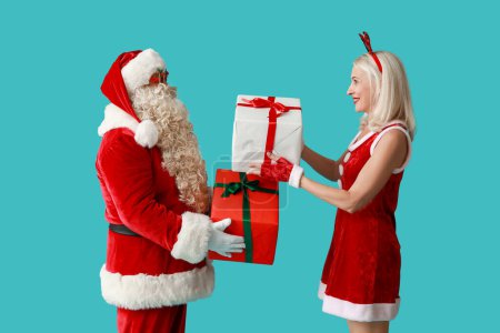 Téléchargez les photos : Père Noël et MRS Claus dans des cornes de cerf de Noël avec des boîtes-cadeaux sur fond bleu - en image libre de droit