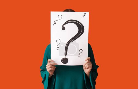 Photo for Young woman holding paper sheet with question marks on orange background - Royalty Free Image