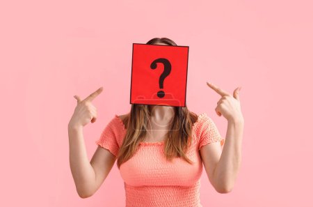 Photo for Young woman pointing at paper sheet with question mark on pink background - Royalty Free Image