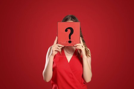 Photo for Young woman holding paper sheet with question mark on red background - Royalty Free Image