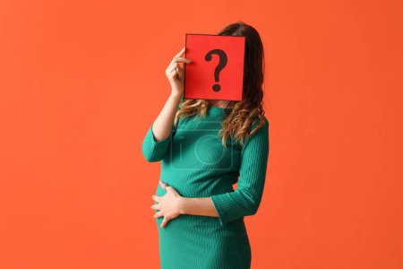 Photo for Young pregnant woman holding paper sheet with question mark on orange background - Royalty Free Image