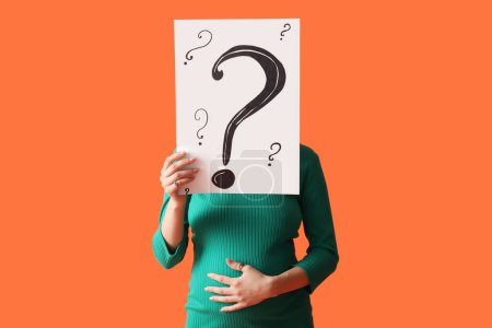 Photo for Young pregnant woman holding paper sheet with question marks on orange background - Royalty Free Image