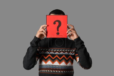 Photo for Young man holding paper with question mark on grey background - Royalty Free Image