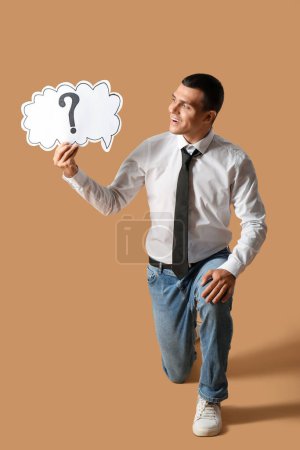 Photo for Young man holding speech bubble with question mark on brown background - Royalty Free Image