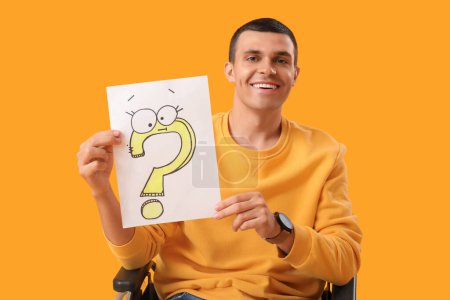 Photo for Young man in wheelchair holding paper with question mark on yellow background - Royalty Free Image