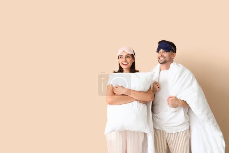 Téléchargez les photos : Jeune couple avec oreiller et couverture sur fond beige - en image libre de droit