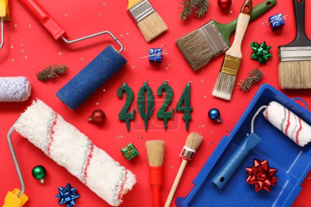 Téléchargez les photos : Composition avec figure 2024 faite de bougies, outils de peintre et décor de Noël sur fond rouge - en image libre de droit