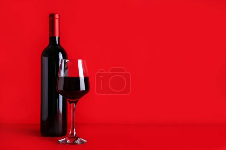 Téléchargez les photos : Bouteille et verre de vin rouge sur fond de couleur - en image libre de droit