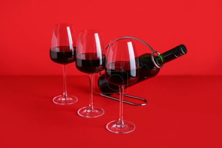 Téléchargez les photos : Bouteille et verres de vin rouge sur fond de couleur - en image libre de droit