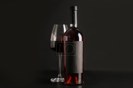 Téléchargez les photos : Bouteille et verre de vin rouge sur fond noir - en image libre de droit