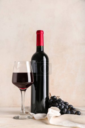 Téléchargez les photos : Bouteille et verre de vin rouge avec raisin sur fond grunge beige - en image libre de droit