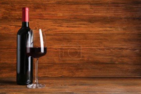 Téléchargez les photos : Bouteille et verre de vin rouge sur fond en bois - en image libre de droit