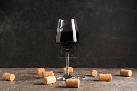 Téléchargez les photos : Verre de vin rouge et bouchons sur table grise sur fond grunge noir - en image libre de droit