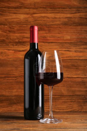 Téléchargez les photos : Bouteille et verre de vin rouge sur fond en bois - en image libre de droit