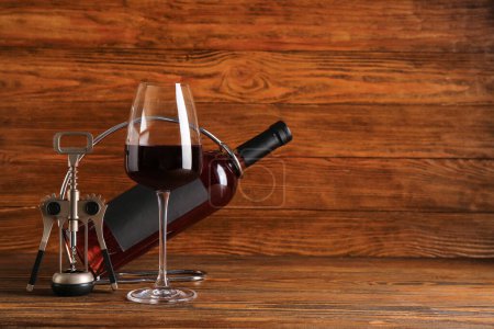 Téléchargez les photos : Bouteille et verre de vin rouge avec tire-bouchon sur fond en bois - en image libre de droit