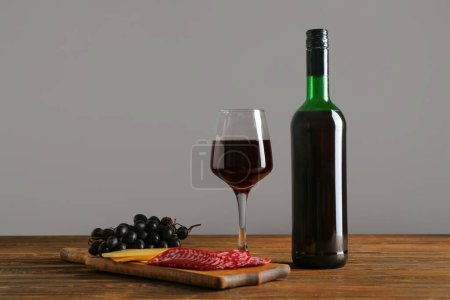 Téléchargez les photos : Bouteille et verre de vin rouge avec collations sur table en bois sur fond blanc - en image libre de droit