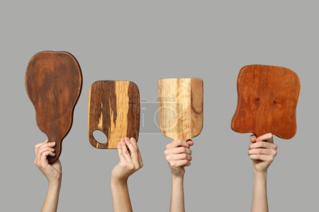 Foto de Manos femeninas con tablas de cortar de madera sobre fondo gris - Imagen libre de derechos