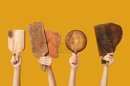 Foto de Manos femeninas con tablas de cortar de madera sobre fondo amarillo - Imagen libre de derechos