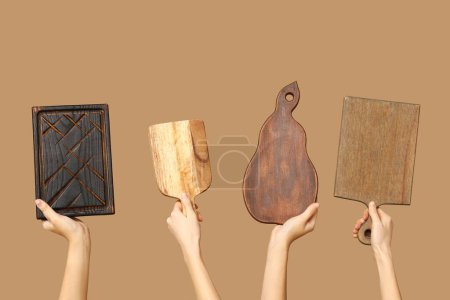 Foto de Manos femeninas con tablas de cortar de madera sobre fondo beige - Imagen libre de derechos