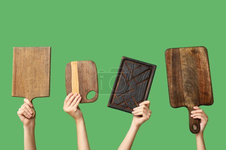 Foto de Manos femeninas con tablas de cortar de madera sobre fondo verde - Imagen libre de derechos