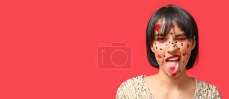 Photo for Grimacing young woman with creative makeup for Valentines Day on red background with space for text - Royalty Free Image