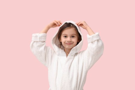 Nettes kleines glückliches Mädchen im Bademantel auf rosa Hintergrund