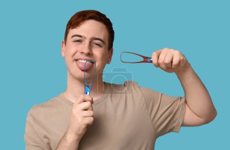 Téléchargez les photos : Jeune homme avec grattoirs de langue sur fond bleu - en image libre de droit