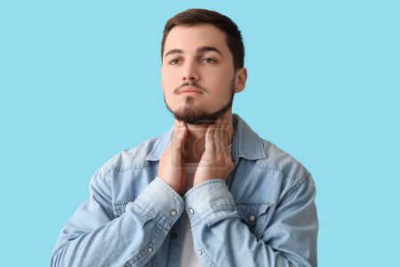 Photo for Young man with thyroid gland problem on blue background - Royalty Free Image