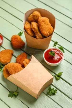 Téléchargez les photos : Boîtes en papier de pépites savoureuses avec ketchup sur fond de bois vert - en image libre de droit