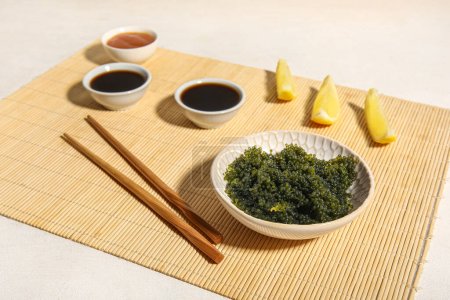 Foto de Composición con tazón de algas sanas, salsas y palillos sobre fondo claro - Imagen libre de derechos