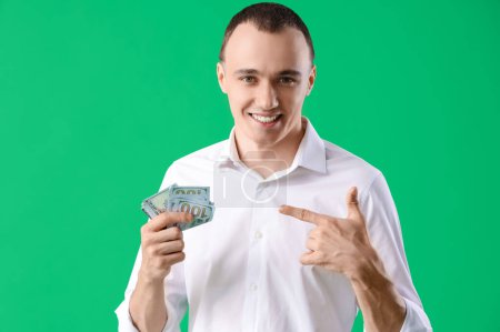 Foto de Joven apuntando al dinero sobre fondo verde, primer plano - Imagen libre de derechos