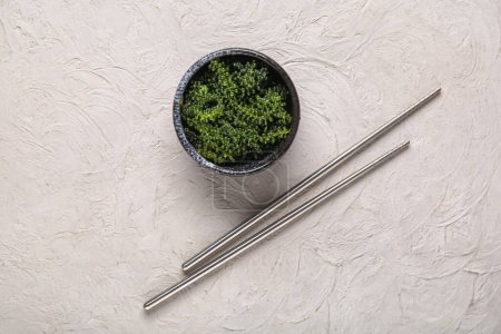 Foto de Cuenco con algas sanas y palillos sobre fondo gris - Imagen libre de derechos