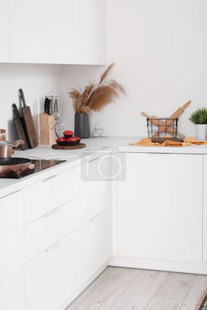 Foto de Encimera de cocina blanca con estufa eléctrica, tablas de cortar y utensilios - Imagen libre de derechos