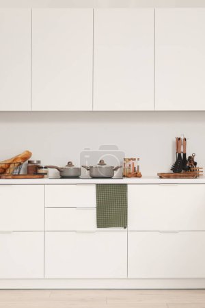 Foto de Mostradores de cocina blancos con tablas de cortar, estufa eléctrica, ollas y utensilios de cocina - Imagen libre de derechos