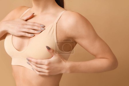Téléchargez les photos : Jeune femme en soutien-gorge sur fond beige, gros plan. Concept de chirurgie plastique - en image libre de droit