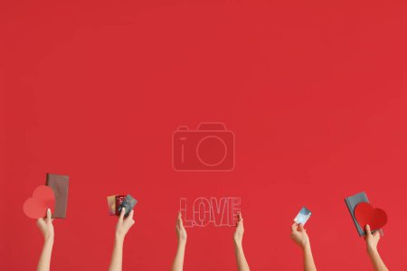 Photo for Women with credit cards, hearts and word LOVE on red background. Valentine's Day celebration - Royalty Free Image