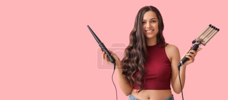Téléchargez les photos : Beautiful young woman holding different curling irons on pink background with space for text - en image libre de droit