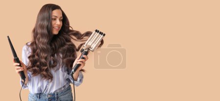 Téléchargez les photos : Beautiful young woman holding different curling irons on beige background with space for text - en image libre de droit