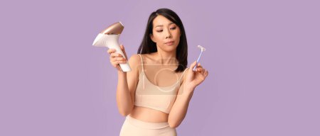 Thoughtful young Asian woman with photoepilator and razor on lilac background