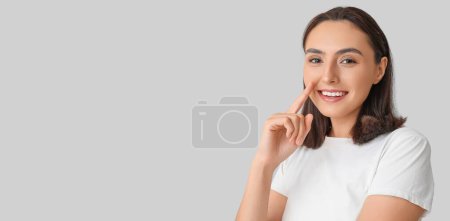 Téléchargez les photos : Young woman pointing at her nose on grey background with space for text - en image libre de droit