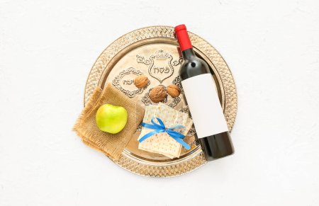 Photo for Passover Seder plate with flatbread matza, bottle of wine, apple and walnuts on light background - Royalty Free Image