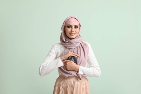 Téléchargez les photos : Young Muslim woman with Koran on green background. Islamic New Year celebration - en image libre de droit