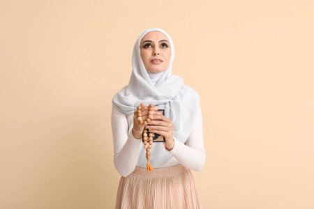 Téléchargez les photos : Young Muslim woman with Koran and prayer beads on beige background. Islamic New Year celebration - en image libre de droit