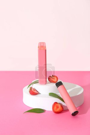 Téléchargez les photos : Podiums décoratifs avec cigarettes électroniques à la fraise sur table rose - en image libre de droit